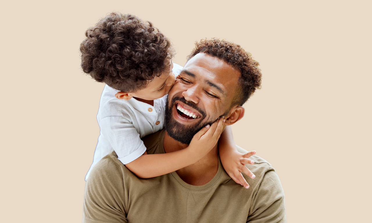 a father with a bright smile receives a kiss on the cheek from his son.