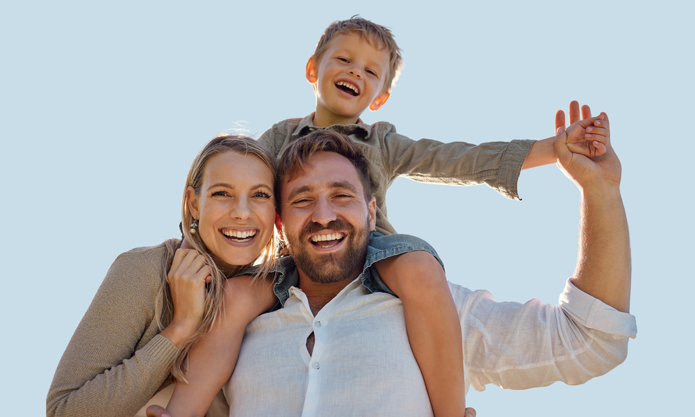 a mother and father stand side by side with a young boy on his father's shoulders