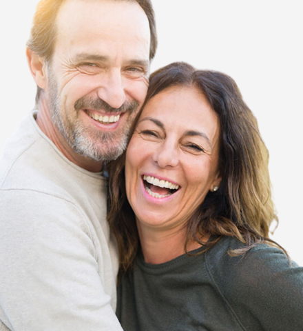 middle aged white couple smile and hug on a white background