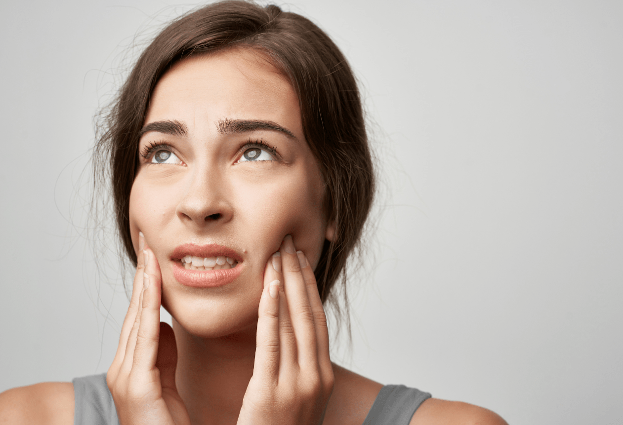 a woman massages her jaw to relieve TMJ/TMD pain