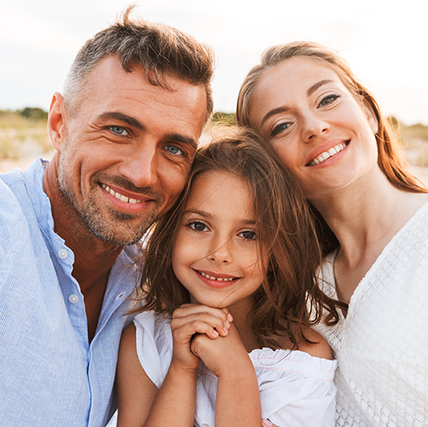 a white family poses together for picture on the beach