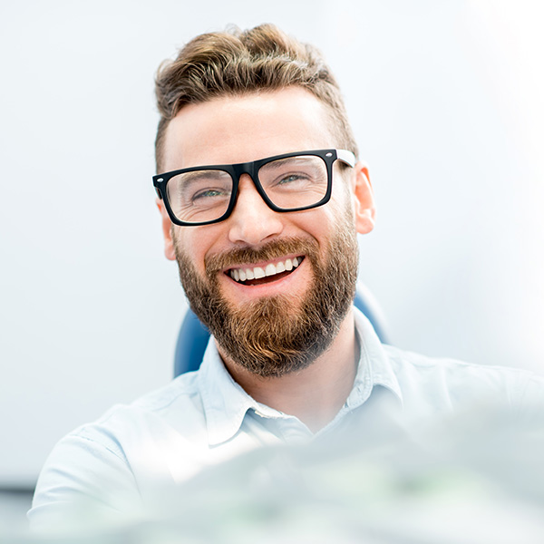 a young man in glasses smiles during a dental visit