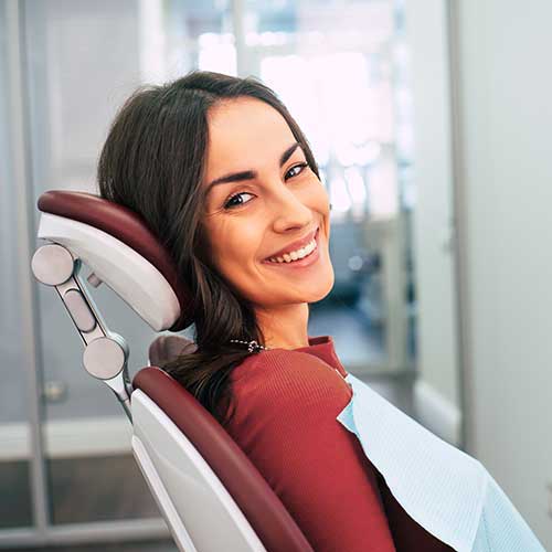 a brunette woman smiles as she waits for a dental cleaning