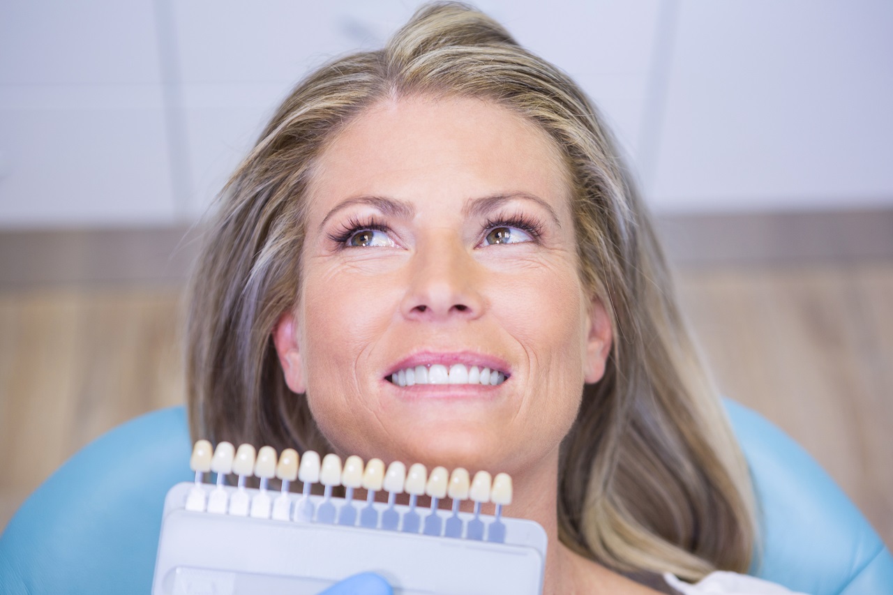 Extreme close up doctor holding tooth whitening equipment by smiling patient at medical clinic