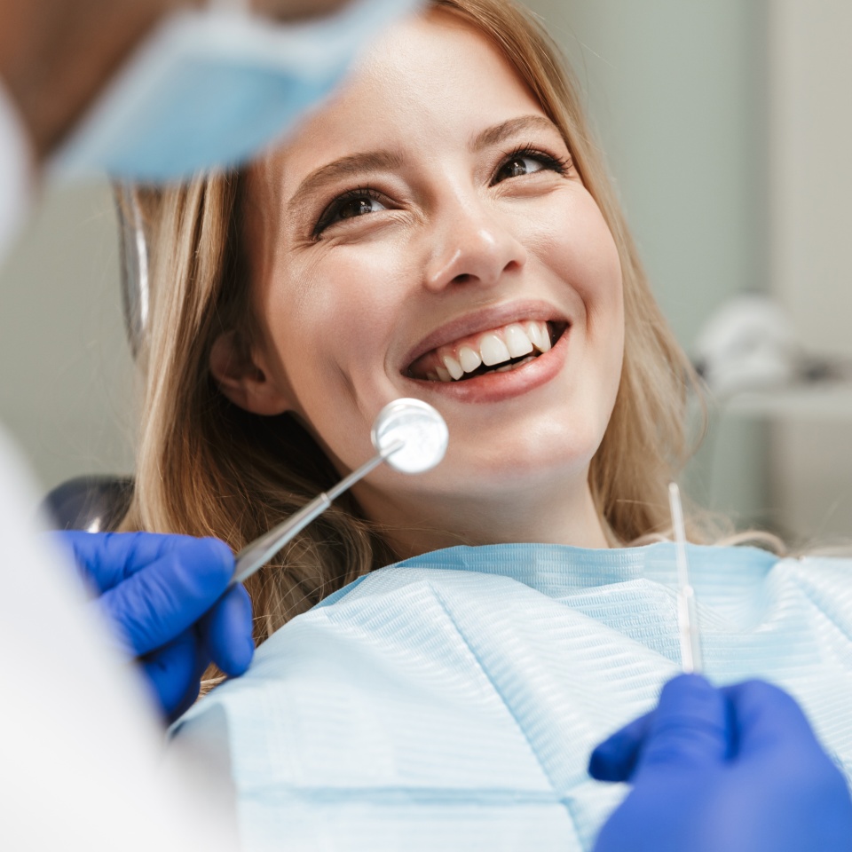 Image of pretty young woman sitting in dental chair at medical center while professional doctor fixing her teeth