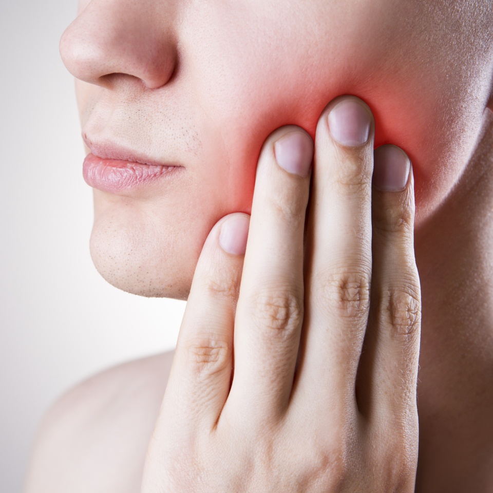 Man with a toothache. Pain in the human body on a gray background with red dot