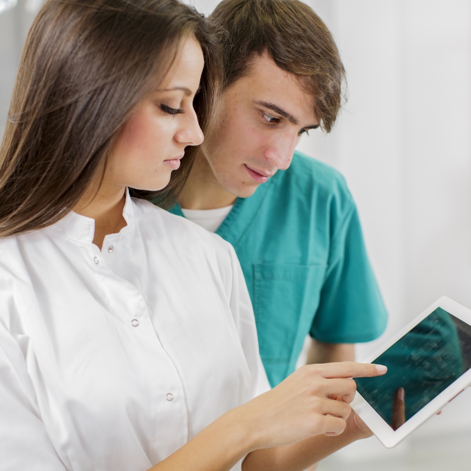 Two young dentists looking at the tablet at work