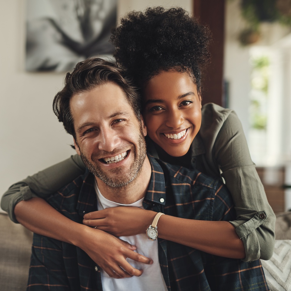 Smile, hug and couple with portrait on sofa for marriage bonding, partnership and romance together. Happy, man and woman with affection on couch at home for love, trust and connection on weekend
