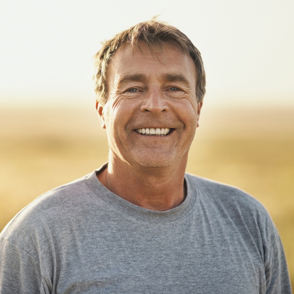 Senior man, smile and portrait at field in summer for outdoor adventure, nature and holiday. Sunshine, happy and face of person by mockup space for weekend vacation, peace and tourism in Turkey