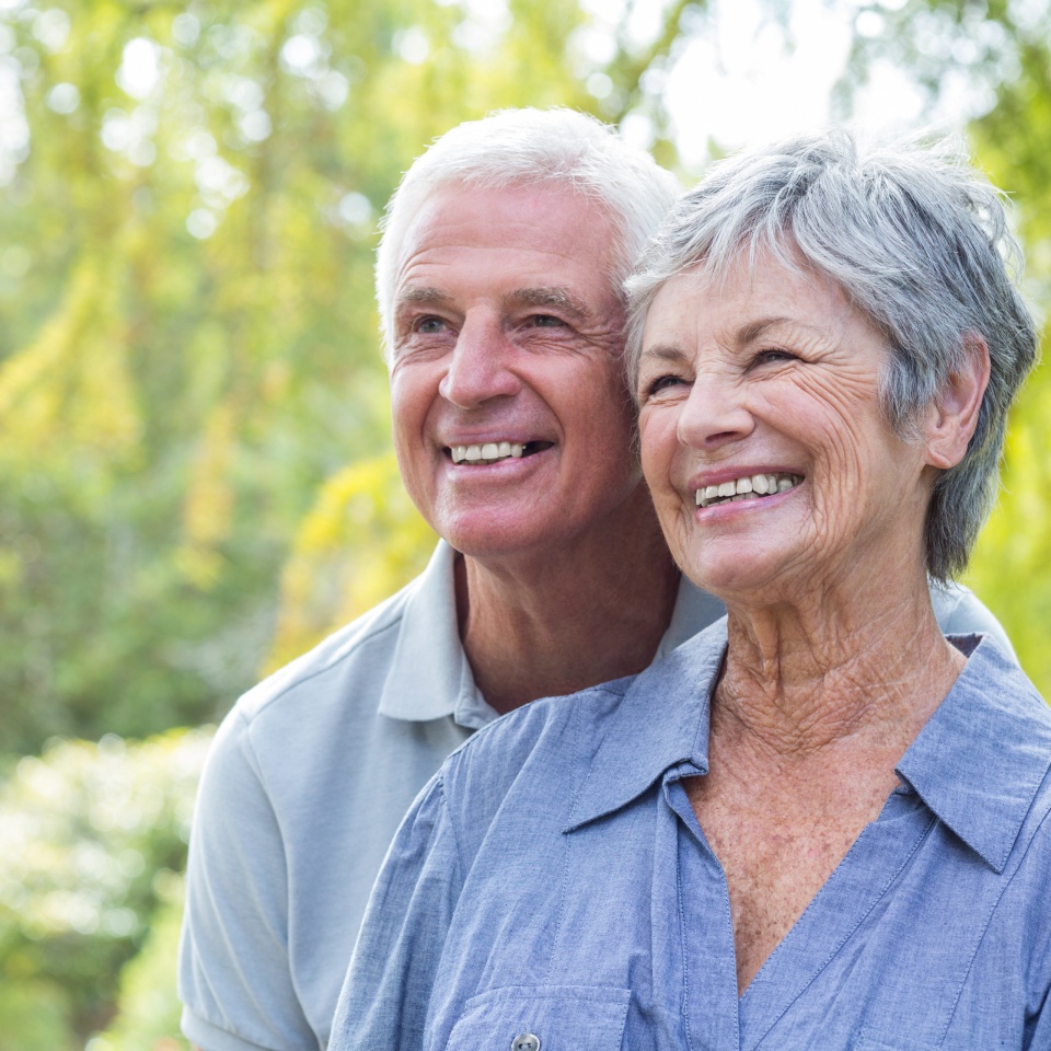 Happy old couple smiling in a park on a sunny day