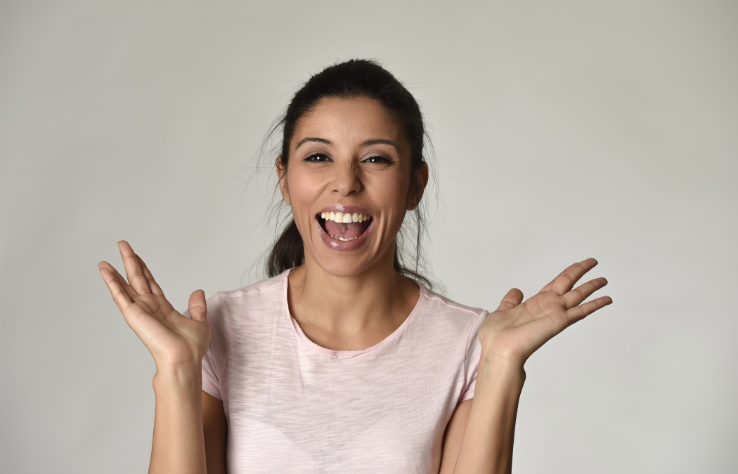 portrait of young beautiful and happy Latin woman with big toothy smile excited and cheerful in charming face expression isolated clear grey background in female happiness emotion